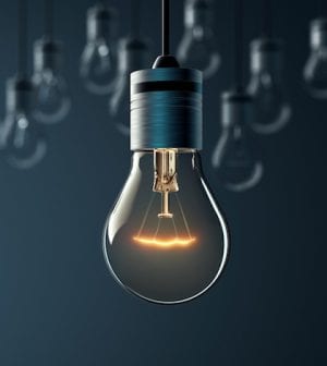 Hanging glowing light bulb on blue background