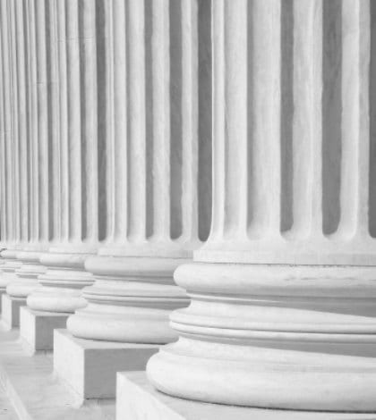 iStock_000006886226SmallPILLARS 420 A row of columns at the entrance to the US Supreme Court in Washington, DC.
Completed in 1935, the US Supreme Court building in Washington, DC, is the first to have been built specifically for the purpose, inspiring Chief Justice Charles Evans Hughes to remark, “The Republic endures and this is the symbol of its faith.”
The Court was established in 1789 and initially met in New York City. When the national capital moved to Philadelphia, the Court moved with it, before moving to the permanent capital of Washington, DC, in 1800. Congress lent the Court space in the new Capitol building, and it was to change its meeting place several more times over the next century, even convening for a short period in a private house after the British set fire to the Capitol during the War of 1812.
The classical Corinthian architectural style was chosen to harmonize with nearby congressional buildings, and the scale of the massive marble building reflects the significance and dignity of the judiciary as a co-equal, independent branch of government.
The main entrance is on the west side, facing the Capitol. On either side of the main steps are figures sculpted by James Earle Fraser. On the left is the female Contemplation of Justice. On the right is the male Guardian or Authority of Law. On the architrave above the pediment is the motto “Equal Justice under Law.” Capping the entrance is a group representing Liberty Enthroned, guarded by Order and Authority, sculpted by Robert Aitken.
At the west entrance are marble figures sculpted by Hermon A. MacNeil. They represent great law givers Moses, Confucius, and Solon, flanked by Means of Enforcing the Law, Tempering Justice with Mercy, Settlement of Disputes between States, and Maritime and other functions of the Supreme Court. The architrave carries the motto “Justice the Guardian of Liberty.”
The interior of the building is equally filled with symbolic ornamentation. The main corridor is known as the Great Hall and contains double rows of marble columns and busts of all former chief justices. At its east end, oak doors open into the Court Chamber, where the justices preside. Most of the second floor is devoted to office space. The library occupies the third floor and has a collection of more than 450,000 volumes.
The Supreme Court consists of the Chief Justice of the United States and eight Associate Justices. The term of the Court begins on the first Monday in October and lasts for the full year. Approximately 8,000 petitions are filed with the Court each term. A further 1,200 applications of various kinds are filed that can be acted upon by a single justice.
The Supreme Court has appellate jurisdiction except “in all Cases affecting Ambassadors, other public ministers and Consuls, and those in which a State shall be Party” (Constitution, art. III, §2), for which it has original jurisdiction. Congress has also from time to time conferred on the Supreme Court the power to prescribe rules of procedure to be followed by the lower courts.