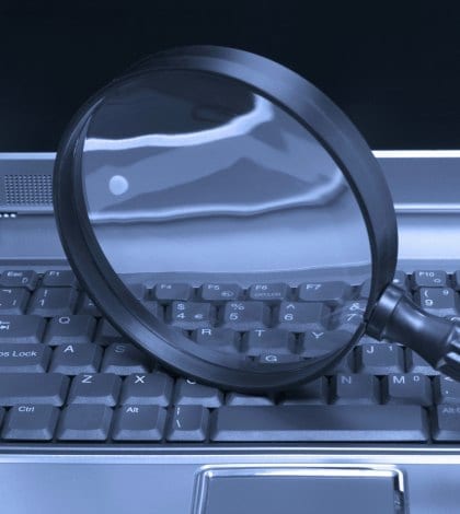 Laptop with a magnifying glass, concept of online security and investigation.