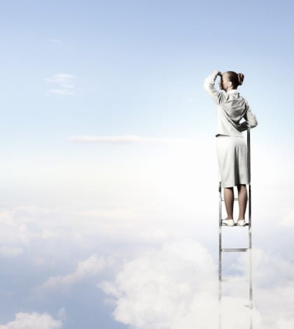 Businesswoman standing on ladder Businesswoman standing on ladder looking into distance against cloudy background