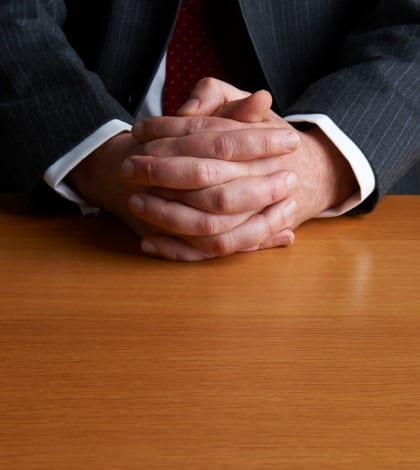 Businessman Sitting At Desk With Folded Hands