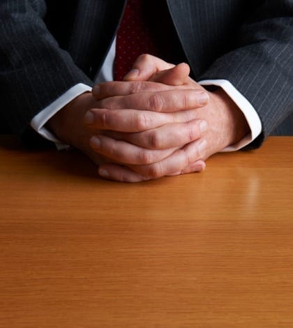 Businessman Sitting At Desk With Folded Hands Businessman Sitting At Desk With Folded Hands