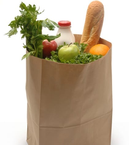 Brown paper bag filled with groceries on a white background