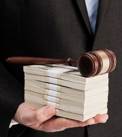 The law and money Man in suit holding stack of money and wooden gavel