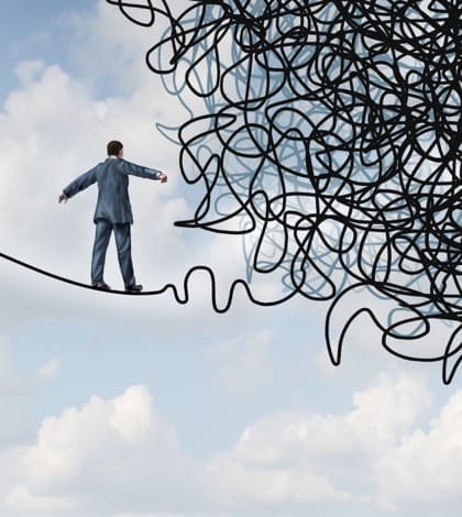 Risk confusion business concept with a businessman on a high wire tight rope walking towards a tangled mess as a metaphor and symbol of overcoming adversity in strategy and finding solutions through skilled leadership facing  difficult obstacles.