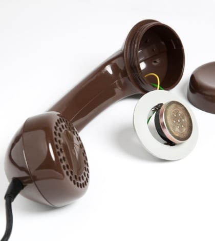 Photo of an old, dirty brown retro telephone with removed earpiece. Image may represent poor quality of connection or wiretapping/telephone bug
