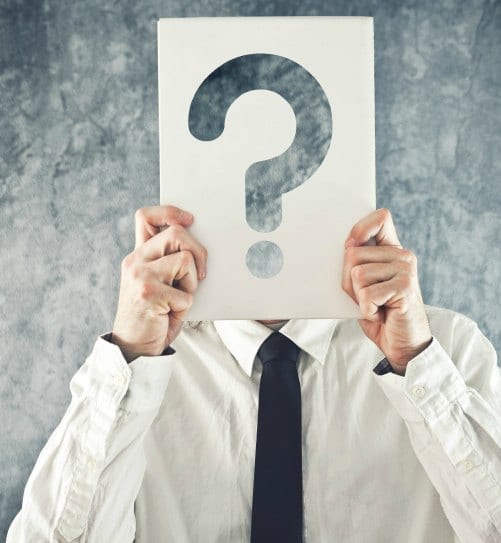 Businessman holding paper with printed question mark in front of his face Businessman holding paper with printed question mark in front of his face