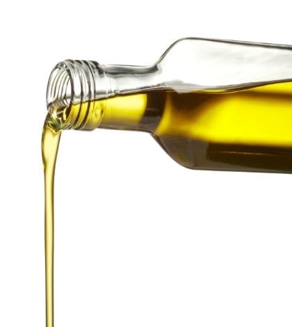 pouring olive oil from glass bottle against white background