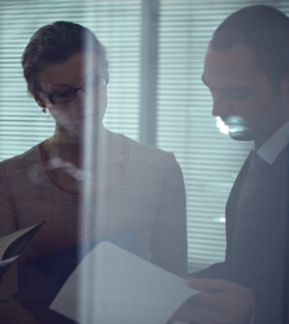 Business people standing together behind window and reading documents Business people standing together behind window and reading documents