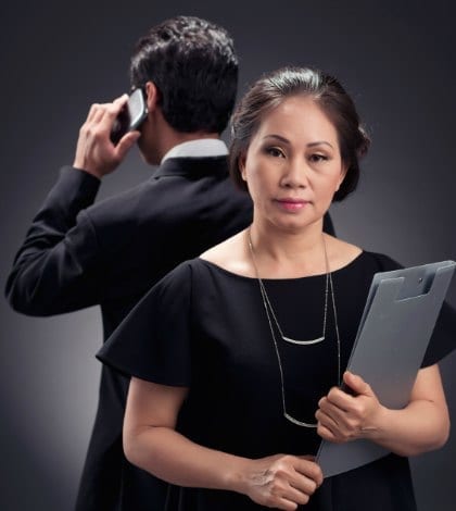 Mature Vietnamese business lady and her male colleague in background Mature Vietnamese business lady and her male colleague in background