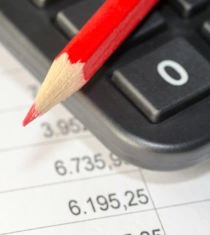 calculator and red pen on the background of financial balance sheets Dolores Giraldez Alonso
