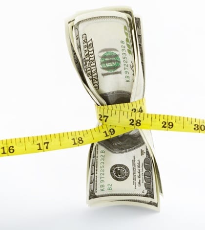 Tight monetary Measuring tape twining several US$100 bills over white background