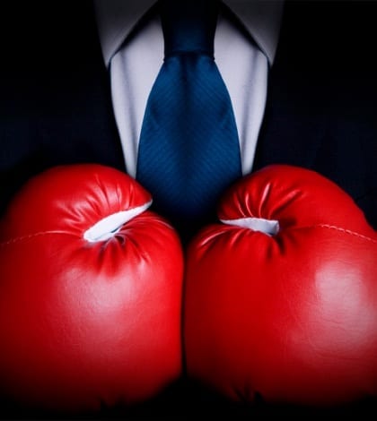 Stock image of person wearing business suit and boxing gloves