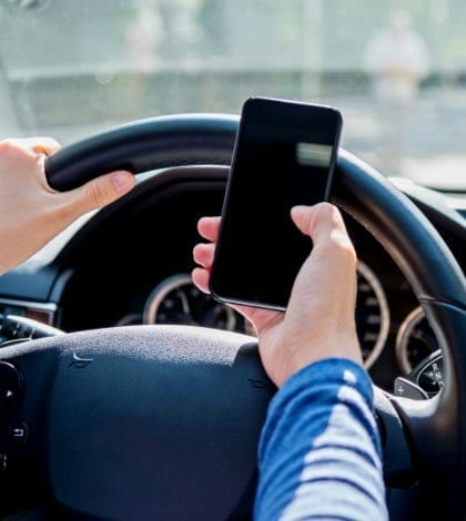 Female driver texting on mobile phone while driving.
