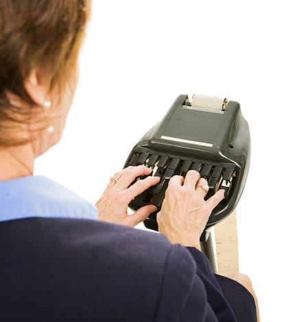 Over the shoulder view of a court reporter using stenography machine.  Isolated on white.