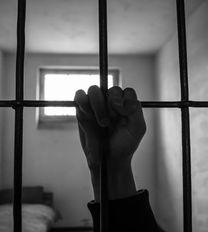 hand of a prisoner grabbed the bars of the prison