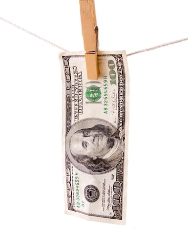 One hundred dollar bill hanging on clothesline with white background.
