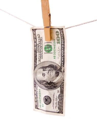 Money Laundering One hundred dollar bill hanging on clothesline with white background.