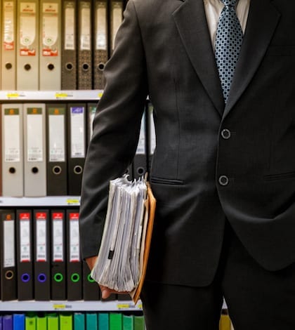 businessman holding data files on binder shelves background