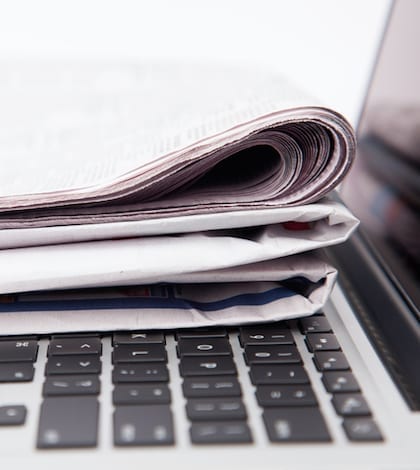 Newspapers resting on laptop keyboard Stack of newspapers resting on laptop keyboard
