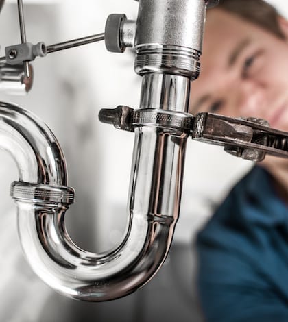 Plumber at work Plumber doing some work under the sink. Tightening siphon.