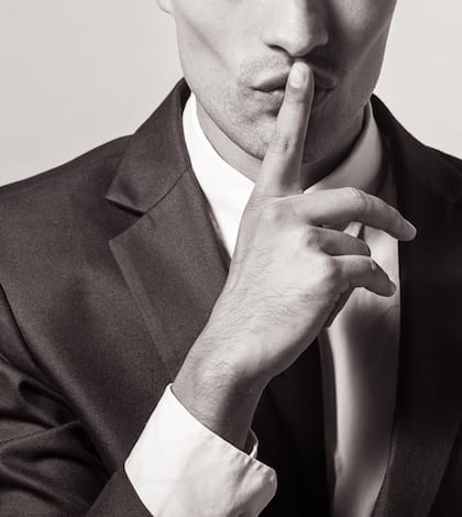 Shhh! Portrait of a young businessman with finger on his lips
