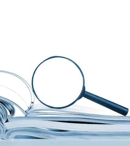 Searching, opened magazines and magnifier glass, side view, isolated white Searching... opened magazines with magnifier glass, side view, isolated on white.
