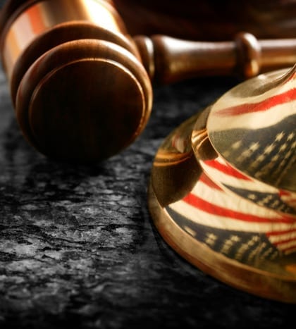 Gavel sitting at base of justice scale with reflection of flag A gavel and the American flag reflected in the base of a justice scale
