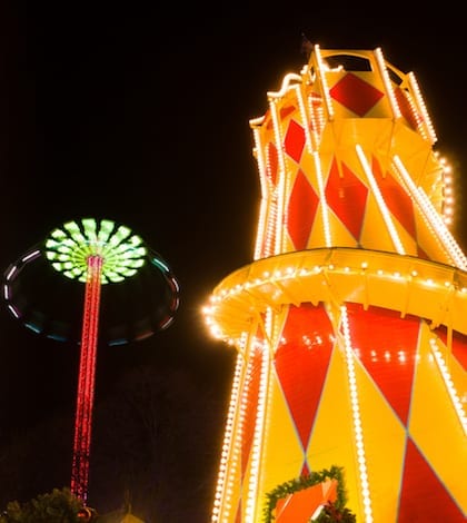 Edinburgh, Scotland - November 22, 2016: Winter festival fairground attractions in Edinburgh, Scotland, part of Edinburgh's Christmas and Edinburgh's Hogmanay 2016. A brightly coloured helter-skelter, with high-rising Star Flyer swing ride in the background next to the Scott monument.