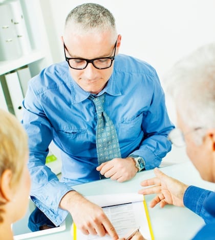 Mature Couple Meeting with Financial Advisor, selective focus to financial advisor pointing to mature woman where to sign contract.