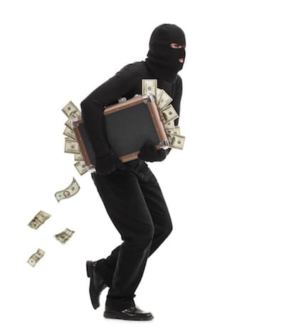 Studio shot of a male burglar with a mask on his head running with a briefcase full of money isolated on white background