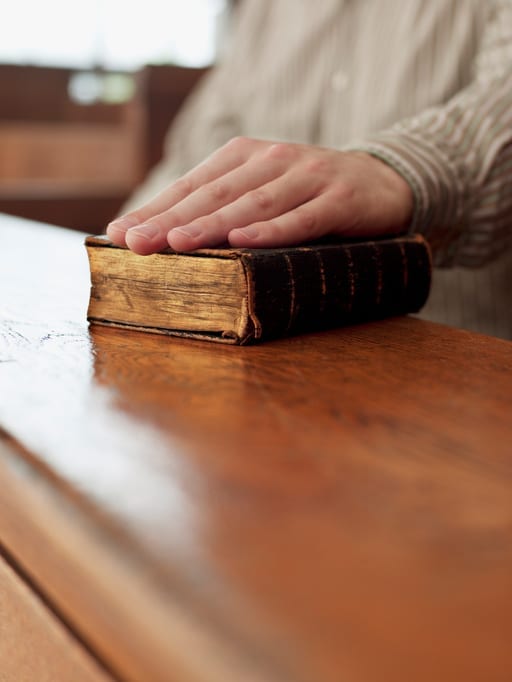 Hand of witness on Bible in courtroom