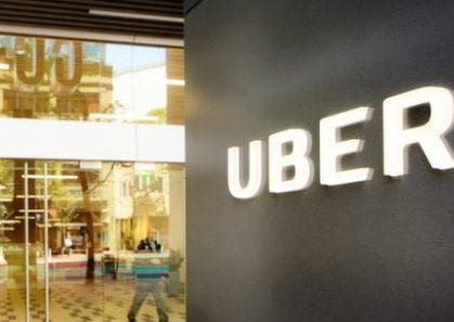 San Francisco, USA - May 12, 2016: Uber headquarters entrance in San Francisco with sign on the right. A woman is leaving the building through the front door. Reflections of Market street in the window.