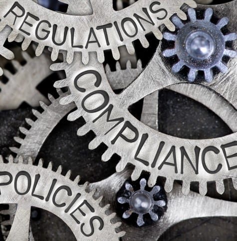 Metal Wheel Concept Macro photo of tooth wheels with COMPLIANCE, REGULATIONS, STANDARDS, POLICIES and RULES words imprinted on metal surface