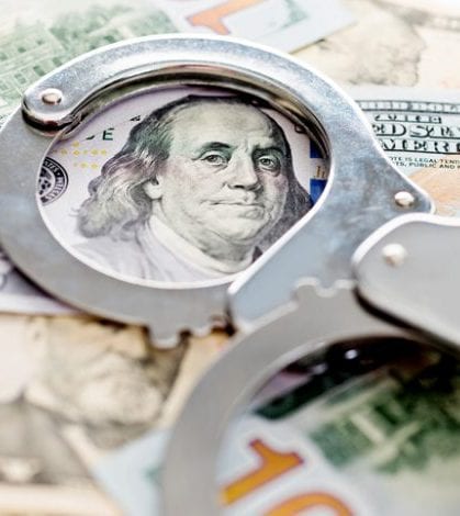 Handcuffs lying on american dollars, financial crime concept.