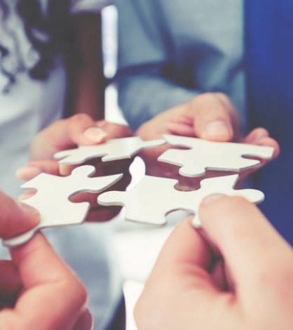 Group of business people holding a jigsaw puzzle pieces. Group of business people holding a jigsaw puzzle pieces. Business solution integration concept. Multi ethnic group. Close up of hands