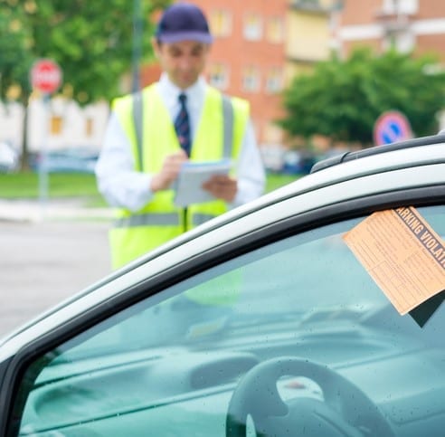 One parking attendant writing a ticket for a parking violation