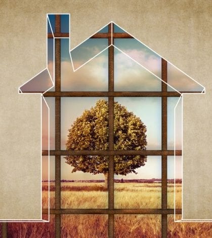The house becomes a prison - House arrest on residential building - concept image with the graphic outline of a small home closed by a metal railing towards a rural scene with a tree The house becomes a prison - House arrest on residential building - concept image with the graphic outline of a small home closed by a metal railing towards a rural scene with a tree.
