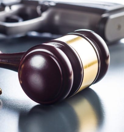 Judge gavel and gun bullets on black table.