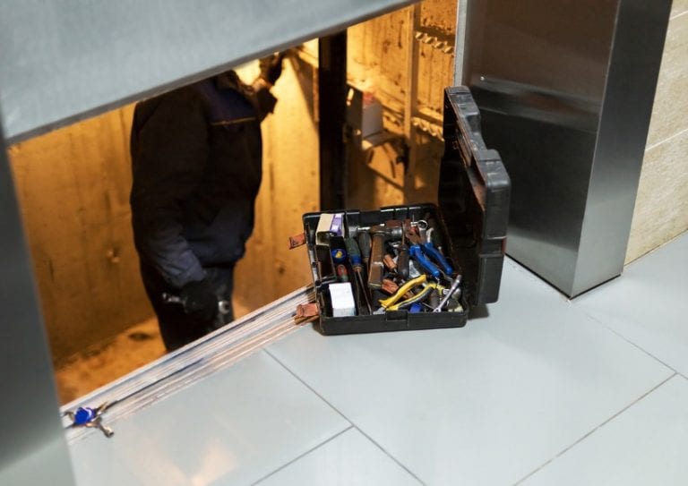 specialist-fixing-or-adjusting-lift-mechanism-in-elevator-schaft-picture-id945628936