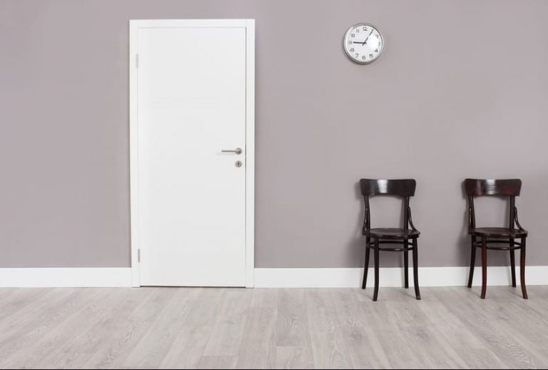Two wooden chairs in a waiting room Two wooden chairs in a waiting room with a clock hanging on the wall above them