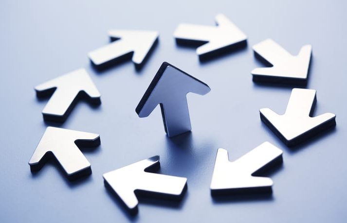 Single Arrow Surrounded By Circle Of Arrows A single arrow points in an upward direction as it is surrounds by a group of arrows forming a circle. The image is photographed with a very shallow depth of field.
