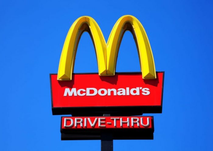McDonald's Sign London, United Kingdom, May 27, 2012 : McDonald's yellow and red drive-thru logo advertising sign placed on a pole with a clear blue sky