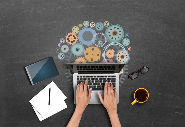 Businesswomen using laptop with gears High angle view of a businessman hands using laptop with gears. Concepts of collaboration and progress.