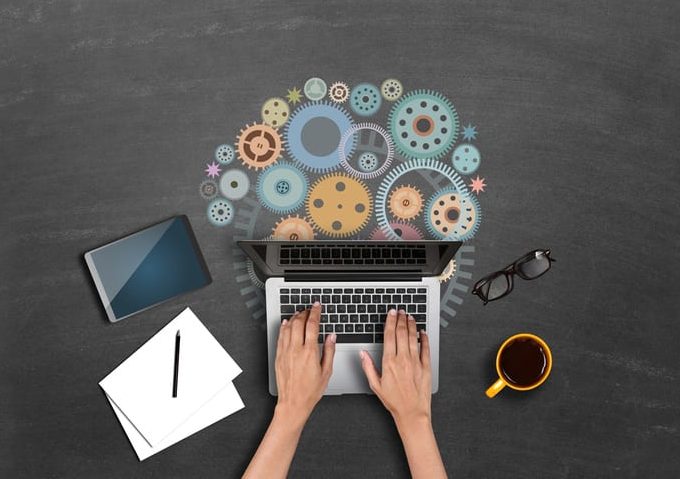 Businesswomen using laptop with gears High angle view of a businessman hands using laptop with gears. Concepts of collaboration and progress.