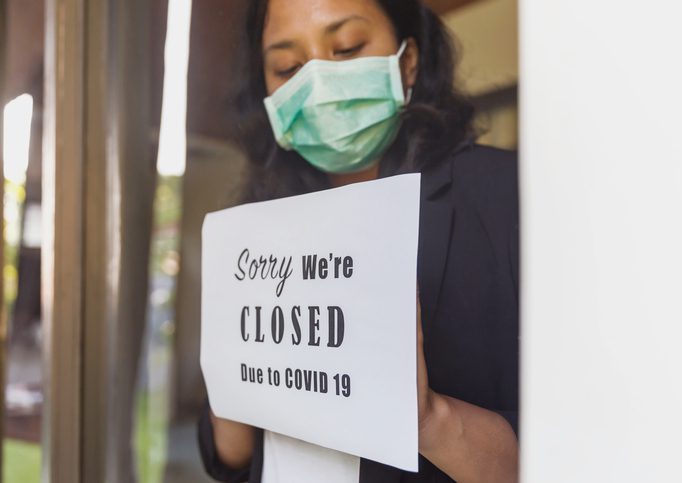 Temporarily close business as COVID-19 outbreak Portrait shot of business owner putting a closing down poster into a window during Covid 19 outbreak