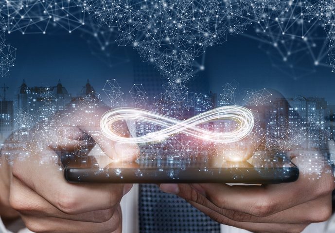 The concept of unlimited Internet. hands holding device with infinity symbol, skyline and constellations in background