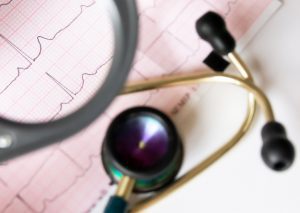 Stethoscope and magnifying glass with patient data chart in the background.