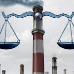 Industrial smokestacks in background, justice scales mounted on big stack in foreground.