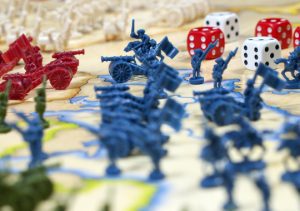 Conflict represented as a board game with dice and combat figures.